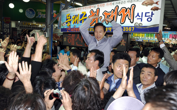 이명박 대통령이 18일 포항시 죽도시장을 방문, 시장 입구에서 상인들을 향해 하트 모양을 만들어 인사하고 있다.  포항 청와대사진기자단