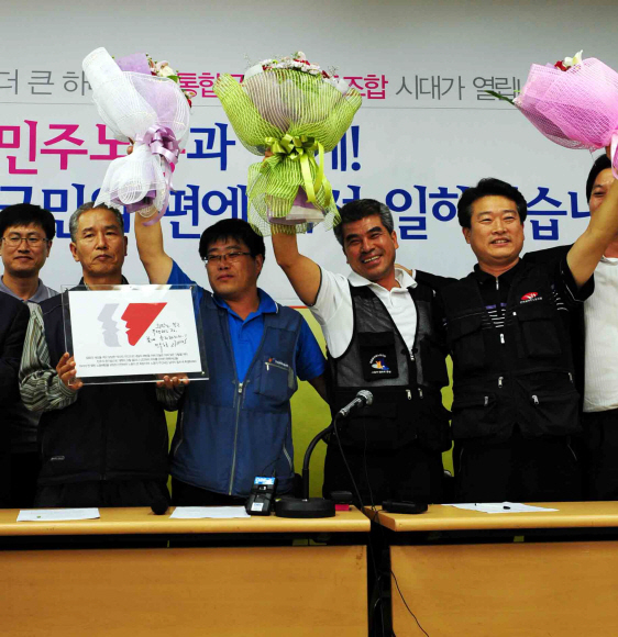 22일 저녁 3개 공무원 노조의 통합과 민주노총 가입이 확정되자 서울 영등포동의 본부에서 투표 결과를 기다리던 공무원 노조 대표자들이 꽃다발을 들며 환호하고 있다.  안주영기자 jya@seoul.co.kr