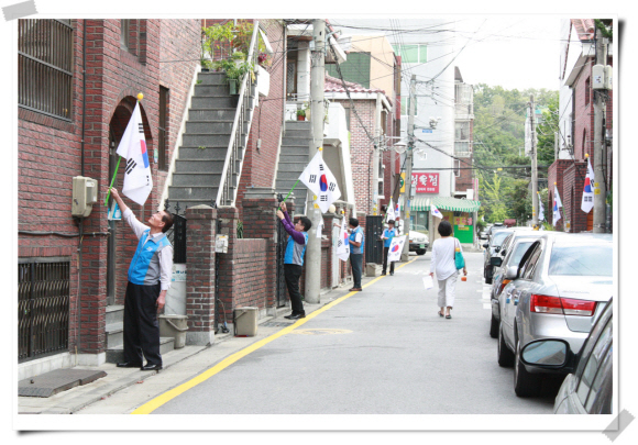 9일 한글날을 맞아 서울 양재2동 태극기 사랑 시민추진위원회 회원들이 지역 주민의 성금으로 마련한 태극기를 집집마다 걸고 있다. 양재2동 주민센터 제공 