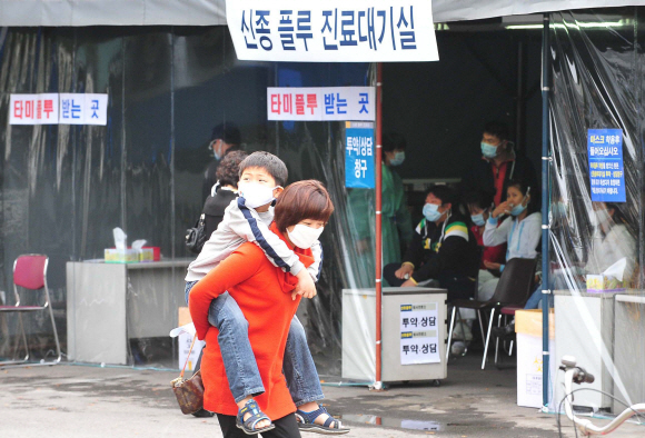 휴일에도 북새통 신종플루 감염환자 수가 주말부터 1만명을 넘어서는 등 상황이 계속 악화되는 가운데 1일 신종플루 검진을 위해 서울 목동 이대병원을 찾은 아이가 엄마의 등에 업혀 병원에 마련된 진료대기실 앞을 지나고 있다. 정부는 이번주 중 국가전염병 위기단계를 최고인 ‘심각’으로 상향 조정키로 하면서 범정부 차원의 재난대책본부를 발족하기로 했다. 손형준기자 boltagoo@seoul.co.kr