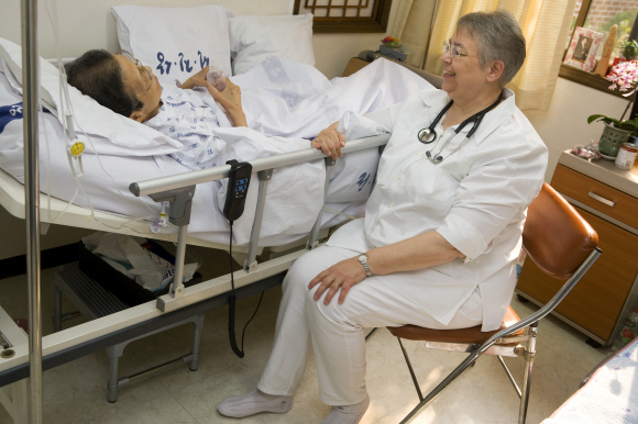 배현정 전진상의원 원장이 18일 여성 노인환자 옆에 앉아 위로하고 있다. 아산사회복지재단 제공