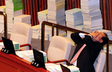 국회 예산결산특별위원회의 내년도 예산안 종합심사 마지막 날인 15일 오전 야당의 불참으로 전체회의가 정회되자, 한 여당 의원이 피로한 듯 기지개를 켜고 있다. 뒤에는 각 상임위에서 넘어온 예산안 관련 서류가 쌓여 있다. 이호정기자 hojeong@seoul.co.kr