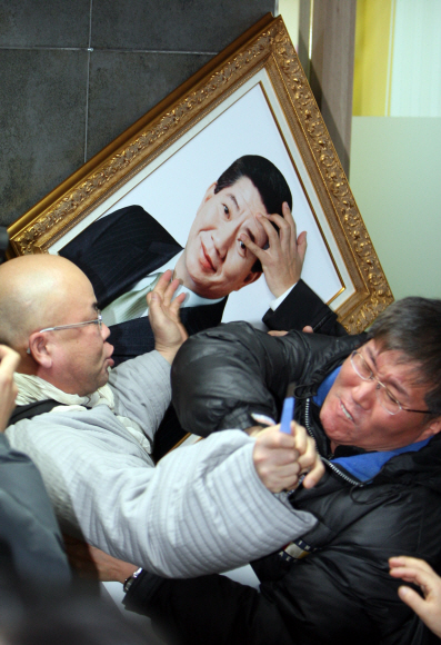 18일 오후 서울 합정동 노무현재단 사무실에서 한 승려가 한명숙 전 총리의 체포에 항의해 문구용 칼을 휘두르자 ‘한명숙 공동대책위’ 관계자가 제지하고 있다. 소동 속에 고 노무현 전 대통령의 사진틀이 떨어지고 있다. 정연호기자 tpgod@seoul.co.kr