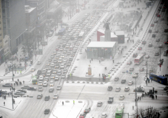 27일 강추위 속에 내린 많은 눈으로 빙판이 된 서울 세종·태평로를 차량들이 거북이걸음으로 운행하고 있다. 손형준기자 boltagoo@seoul.co.kr