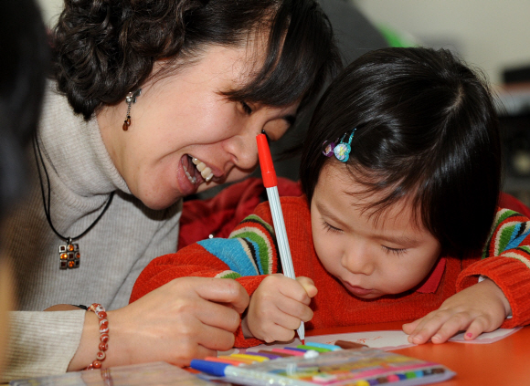 서울 삼청동 국립민속박물관 내 어린이박물관에서 진행된 만 4세 유아 대상 교육프로그램에서 한 아이가 엄마와 함께 만든 연꽃카드에 글씨를 쓰고 있다.