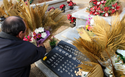 김수환 추기경 선종 1주기를 하루 앞둔 15일 경기 용인 천주교 성직자 묘지를 찾은 한 시민이 묘역에 꽃을 올리고 있다. 연합뉴스