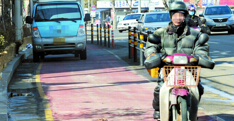18일 오후 서울 천호대로 아차산역 부근 자전거 전용도로에서 한 오토바이 운전자가 불법 정차한 택배 트럭과 안전펜스 사이의 좁은 공간을 곡예운전하듯 아슬아슬하게 운행하고 있다.  도준석기자 pado@seoul.co.kr