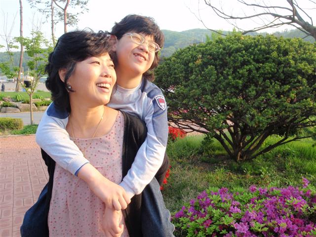 10일 김진미씨가 경기 광주 삼육재활병원 뜰에서 8년 전에 입양한 영운이를 업고 즐겁게 대화하고 있다.