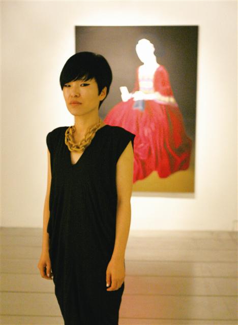 이소연이 자신의 얼굴을 닮은 여성을 그린 작품 ‘붉은 드레스’ 앞에 서 있다.  카이스갤러리 제공