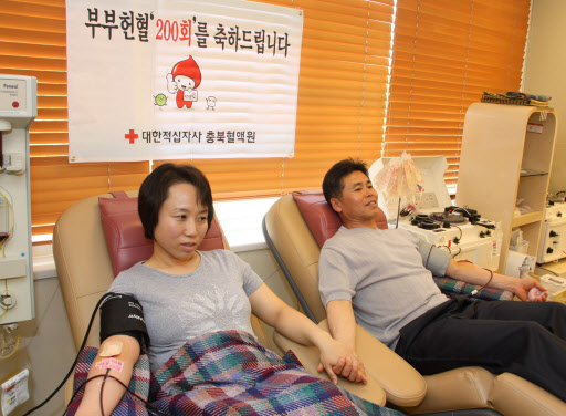 함석문(오른쪽)씨 부부가 20일 다정스러운 모습으로 헌혈하고 있다.  연합뉴스 