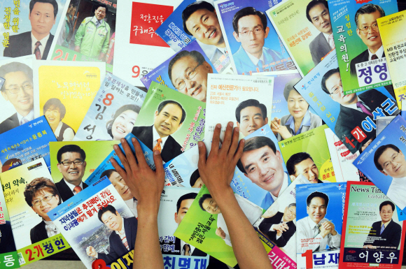 30일 서울 종로구의 한 유권자가 집으로 배달된 수많은 선거공보물을 방안에 펼쳐 놓고 살펴보고 있다. 서울 관악구 등 32개 지역에는 각각 51명의 후보가 출마해 공보물이 500여쪽에 이른다. 정연호기자 tpgod@seoul.co.kr