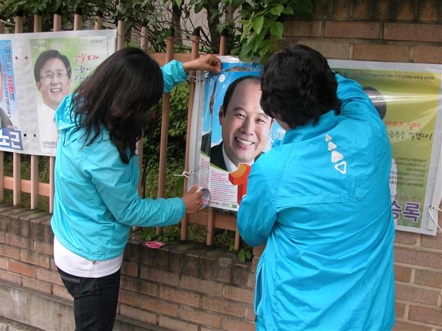 31일 서울 하계동의 한 길가에서 ‘벽돌이’로 활동하는 여성들이 훼손된 선거 벽보를 교체하고 있다.