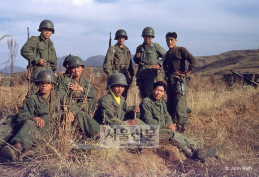 국군들의 망중한. 앞 줄 오른쪽에서 두번째 앉아있는 병사의 노란 마후라가 눈에 띈다. 한국전쟁에 참전한 국군은 60만명에 달하고 이들 중 13만 7899명이 전사, 45만 742명이 부상을 당했다. 전쟁 초반 국군은 낙동강 전선까지 밀렸지만 계속되는 교전을 통해 유엔군의 주력군으로 자리잡았다. 종군기자 존 리치의 ‘컬러로 보는 한국전쟁’에 실렸다.