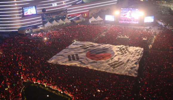 축제는 아직 끝나지 않았어  한국-아르헨티나전이 열린 17일 밤 서울광장에 모여 경기를 관전하던 시민들이 대형 태극기를 이용한 응원을 펼치고 있다. 사진공동취재단