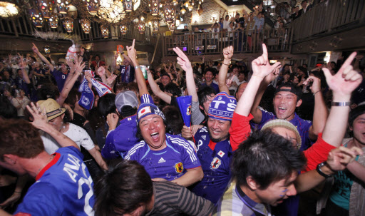 일본 축구 서포터스 ‘울트라닛폰’이 일본-카메룬전이 벌어진 14일 도쿄에서 대형TV를 보며 첫 골을 자축하고 있다. 도쿄 AP 특약