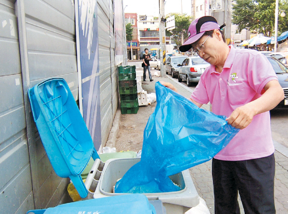 윤동규 영등포구 구의원은 아침 6시 신길동 시장 주변에 버려진 음식물 쓰레기를 옮겨, 전용 수거용기에 버리고 있다.
