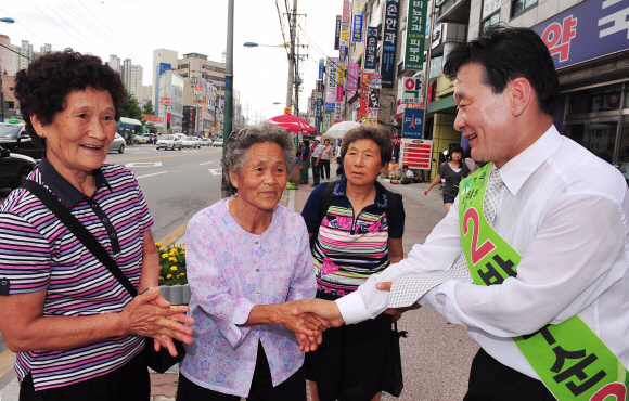 강원 원주에 출마한 민주당 박우순(오른쪽) 후보가 지난 21일 원주 남부시장에서 유권자들을 만나 악수를 하며 한 표를 호소하고 있다. 원주 이언탁기자 utl@seoul.co.kr