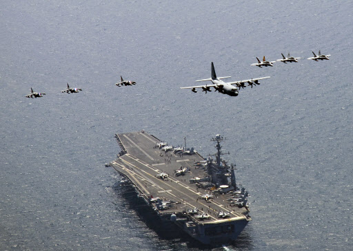 미 해군의 C-130 허큘리스 수송기(가운데 비행기)가 F/A-18A/C 호넷과 A/V-8B 해리어의 엄호를 받으며 핵 항공모함 조지워싱턴호 위로 날아가고 있다. 미 해군 제공