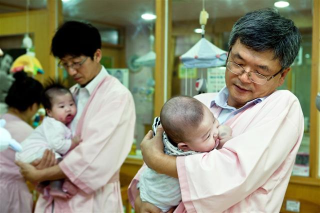 ‘자원봉사축제’에 참석한 이종철(오른쪽) STX그룹 부회장이 서울 영아일시보호소에서 아기를 돌보고 있다. STX 제공