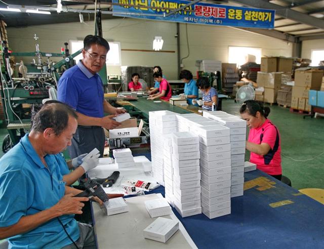 경기 파주의 박스 제조업체인 메자닌아이팩 공장에서 박상덕(왼쪽 두 번째) 사장과 직원들이 종이 박스를 만들고 있다. 이 회사는 새터민과 저소득층의 일자리 제공을 위해 SK그룹이 지원하는 사회적기업이다.  SK 제공