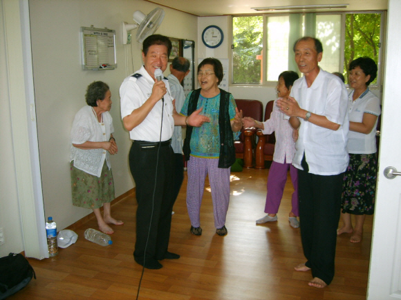 경찰가수 류돈수(왼쪽) 경위가 경기 부천시 소사구의 한 경로당에서 노래로 흥을 돋우자 노인들이 손뼉을 치며 흥겹게 따라 부르고 있다. 부천 소사경찰서 제공 