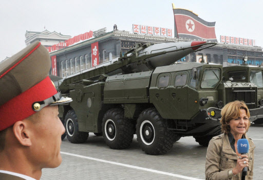 10일 조선노동당 창건 65주년 기념 열병식에 처음 공개된 북한의 신형 중거리탄도 미사일(IRBMs) ‘무수단’으로 추정되는 미사일 앞에서 스페인 공영방송 ‘tve’의 여기자(오른쪽)가 행사를 보도하고 있다. 방송하는 여기자를 바라보는 북한 병사의 모습이 이채롭다.  평양 AP연합뉴스