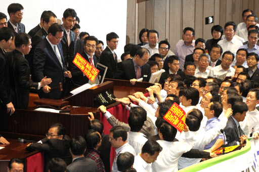 국회 정의화 부의장이 지난 8일 오후 국회 본회의에서 야당 의원들의 반발속에 새해 예산안을 통과시키는 순간 야당의원들이 던진 손피켓이 정 부의장 앞으로 날아들고 있다.  연합뉴스