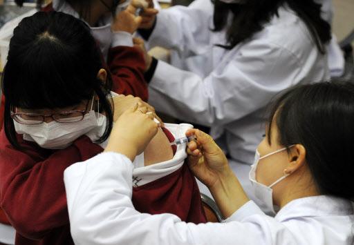 마스크를 쓴 학생들이 신종플루 예방접종 주사를 맞고 있다.  연합뉴스(자료사진) 