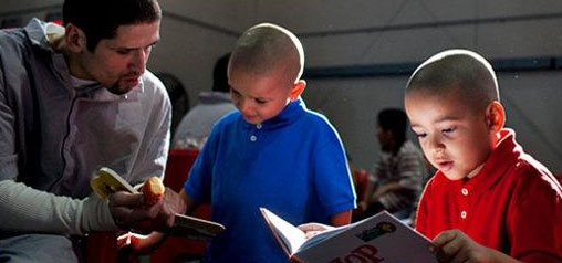 뉴욕 리커스 섬 교도소에서 재소자 호세 로사도(왼쪽)가 아이들에게 동화책을 읽어주고 있다.  뉴욕타임스