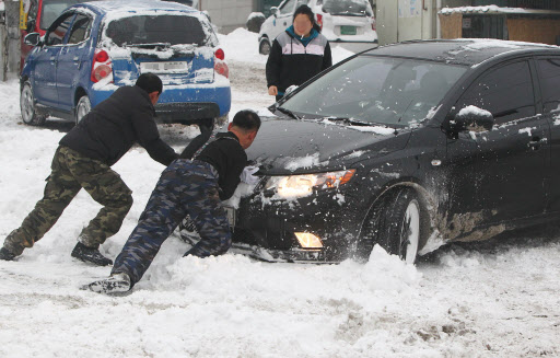28일 오전 경기도 포천시 소흘읍에서 시민들이 눈에 빠진 차량을 밀고 있다. 연합뉴스