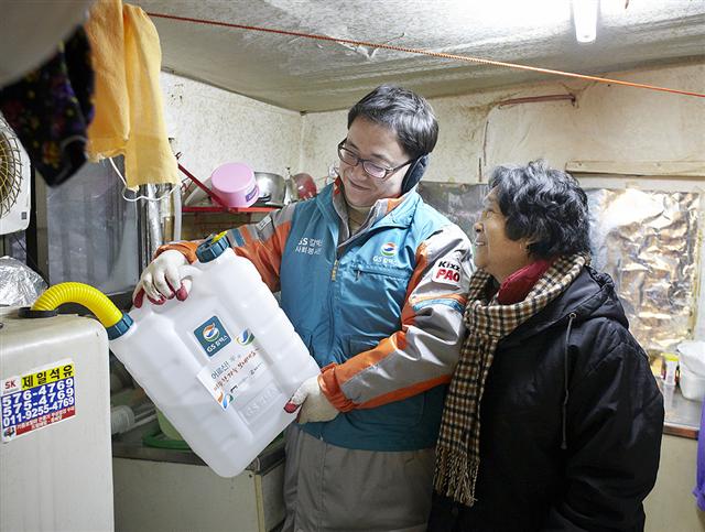 GS칼텍스 직원(왼쪽)이 서울 개포동 구룡마을에서 지역 주민에게 난방유를 전달하고 직접 보일러에 넣어주고 있다. GS칼텍스 제공