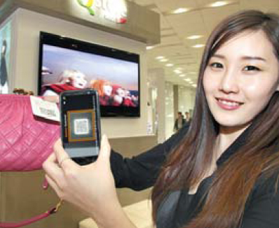 22일 SKT 서울 을지로 본사 지하에 개점한 ‘Q스토어’에서 홍보 도우미가 스마트폰으로 QR코드를 스캔해 상품을 구입하는 모바일 커머스를 시연하고 있다.  SKT 제공