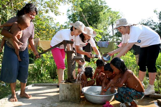 웅진코웨이 우수고객들이 2009년 11월 캄보디아의 한 마을에 우물을 설치한 뒤 아이들을 씻기고 있다. 웅진코웨이 제공