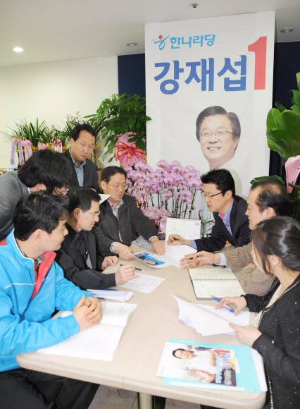 강재섭 한나라당 후보의 선거참모들이 11일 강후보의 대형사진이 걸린 선거 사무실에서 전략 회의를 하고 있다. 이호정기자 hojeong@seoul.co.kr