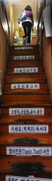한 수험생이 노량진 고시촌 서점의 계단을 오르고 있다. 계단마다 시험 종류 등의 문구가 붙어 있다.