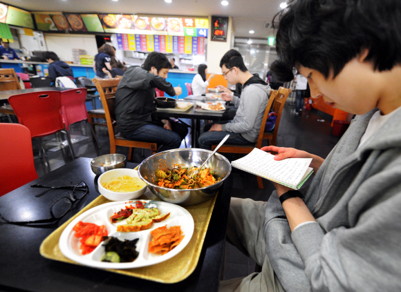 한 수험생이 시간이 아까운 듯 식사 중에도 메모를 해 가며 공부하고 있다.