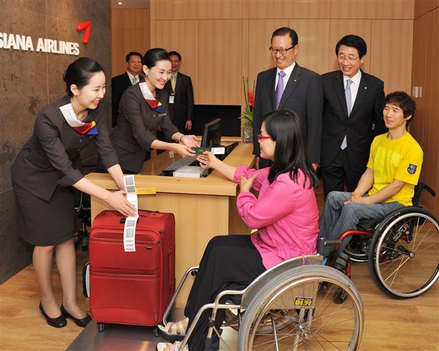 윤영두(뒷줄 오른쪽 세번째) 아시아나항공 사장과 한태근(두번째) 서비스본부장이 지켜보는 가운데 장애인 고객들이 15일 문을 연 ‘한사랑 라운지’에서 직원의 서비스를 받고 있다.  정연호기자 tpgod@seoul.co.kr