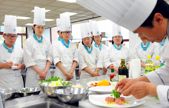 한국조리과학고등학교 학생들이 음식을 맛깔스럽게 장식하는 모습을 지켜보고 있다.