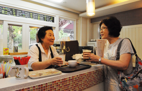 ‘실버 바리스타’로 일하는 손옥경(왼쪽) 할머니가 지난 12일 서울 서대문구 남가좌동 서대문종합사회복지관 내 커피숍에서 손님에게 커피를 만들어 전달하고 있다.  