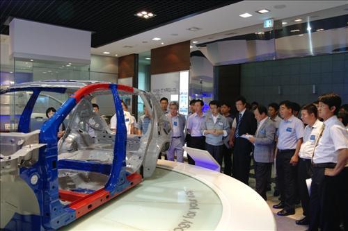 지난 19일 기업 벤치마킹을 위해 부산의 성우하이텍을 찾은 삼성전자 임직원들이 홍보관에서 자동차 관련 기술에 대해 설명을 듣고 있다.  삼성전자 제공