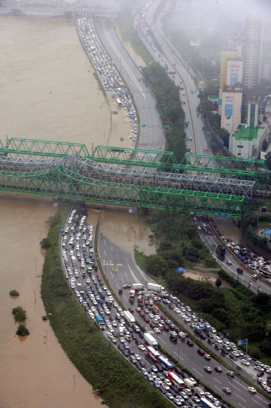 27일 오전 서울 올림픽대로 김포공항 방향 한강철교 근처의 도로가 물에 잠겨 차들이 꼼짝하지 못하고 있다.