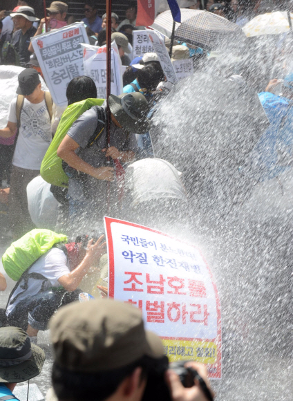 28일 오후 서울 용산구 갈월동 한진중공업 본사 앞에서 열린 제4차 ‘희망버스’ 집회에서 도로를 점거한 참가자들이 경찰이 쏘는 물대포를 맞고 있다. 경찰은 불법적인 도로점거에 대처하기 위한 수단이라고 설명했다. 안주영기자 jya@seoul.co.kr