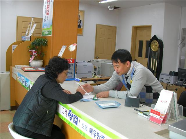 충북 영동군 매곡면 매곡우체국 양영일(오른쪽) 사무주임이 모처럼 우체국을 찾은 장계옥(68) 할머니에게 적금 가입 절차에 대해 설명하고 있다.