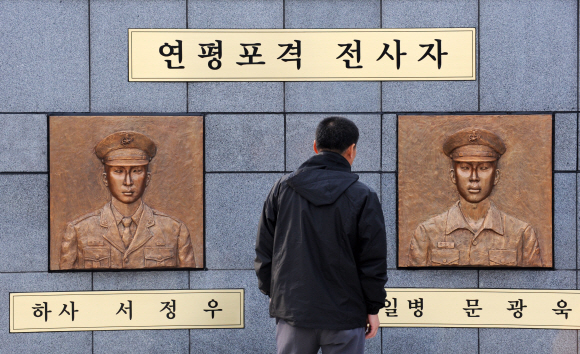 지난 16일 인천 옹진군 연평도 평화공원을 찾은 한 주민이 1년 전 북한의 포격으로 숨진 전사자들을 추모하는 황동 부조상을 살펴보고 있다.  연평도 도준석기자 pado@seoul.co.kr