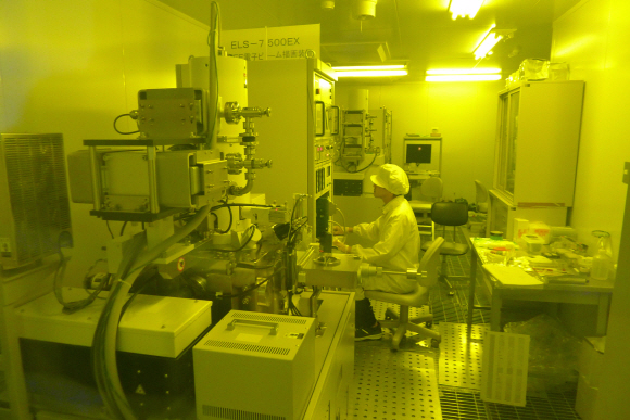 에리오닉스 본사의 한 연구원이 고청정 진공 작업실에서 완성 단계의 나노측정기를 쳐다보며 기기의 각종 기능을 시험해 보고 있다.
