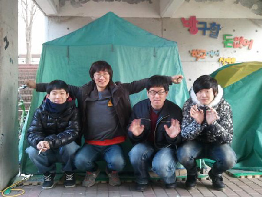 성공회대 노숙 모임인 ‘꿈꾸는 슬리퍼’ 소속 학생들이 교내에 설치한 텐트 앞에 모여 앉아 환하게 웃고 있다.