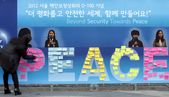 ‘2012 서울 핵안보정상회의’를 100일 앞둔 16일 오전 서울 중구 명동에서 열린 D-100 대국민 참여 행사에서 한 시민이 길거리에 마련된 대형 현수막에 평화의 메시지를 붙이고 있다. 연합뉴스