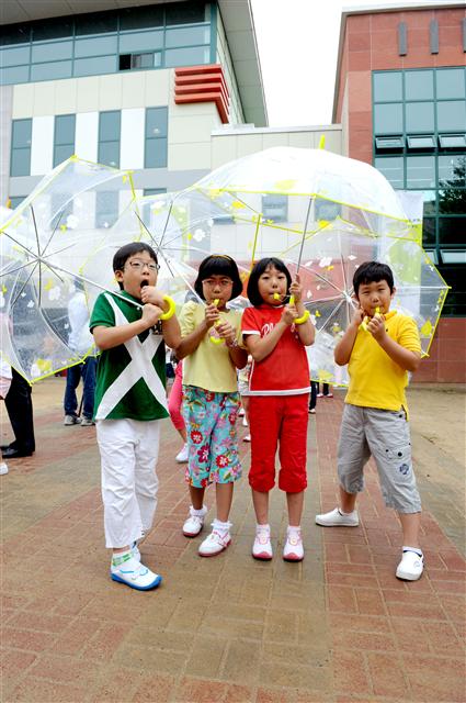 어린이들이 지난 8월 현대모비스가 무료로 나눠 준 투명 우산을 쓰고 기념사진을 찍고 있다.  현대모비스 제공