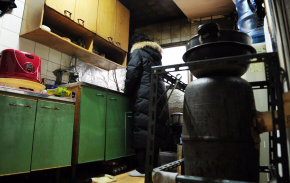 30일 오후 서울 종로구 창신동의 한 낡은 집에 세들어 사는 정모(65)씨가 두꺼운 외투를 입고 주방일을 하고 있다.  손형준기자 boltagoo@seoul.co.kr