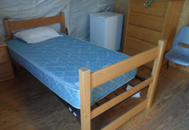 관타나모 기지 훈련 장병 막사 내 침대 모습. 침대 오른쪽 옆으로 흰색 소형 냉장고와 서랍장이 보인다.